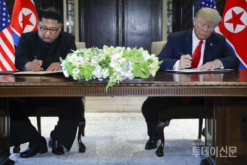 김정은(왼쪽) 북한 국무위원장과 도널드 트럼프 미국 대통령이 지난 6월 12일 싱가포르 카펠라 호텔에서 북미 정상회담을 마치고 합의문에 서명하고 있다. ⓒAP/뉴시스