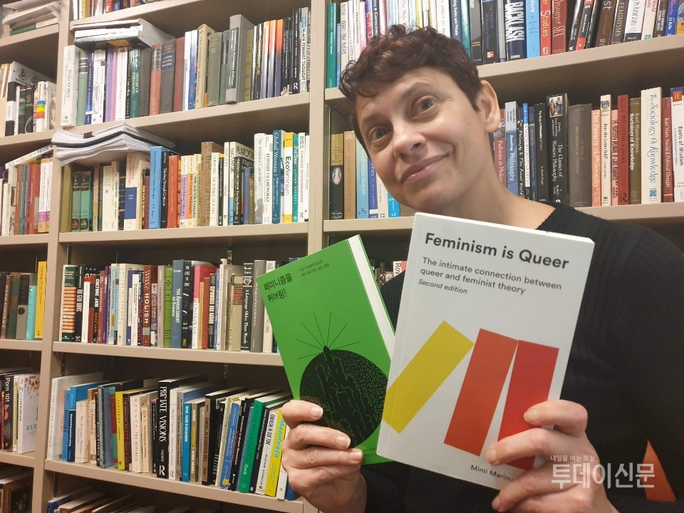 미미 마리누치 교수가 지난 ~일 미국 이스턴 워싱턴 주립대학교 자신의 연구실에서 페미니즘을 퀴어링!(Feminism is Queer)를 들고 사진 촬영을 하고 있다.