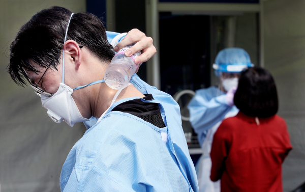 의료진이 생수를 목에 대며 더위를 식히고 있다.