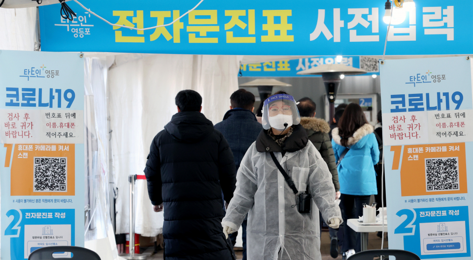 코로나19 신규 확진자가 7,513명으로 3일 연속 7천 명대를 기록한 24일 오전 서울 영등포구 여의도공원 임시선별검사소에서 의료진이 검사를 기다리는 시민들을 통제하고 있다.