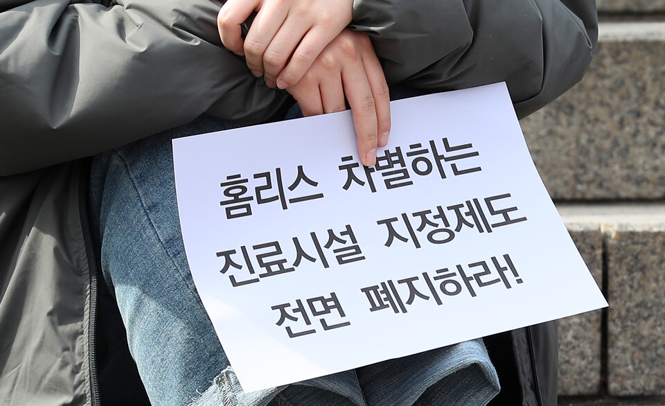 10일 오후 서울 중구 서울역광장에서 열린 노숙인 진료시설 지정제도 전면폐지 촉구 결의대회에서 한 참석자가 피켓을 들고 있다.&nbsp; [사진제공=뉴시스]<br>