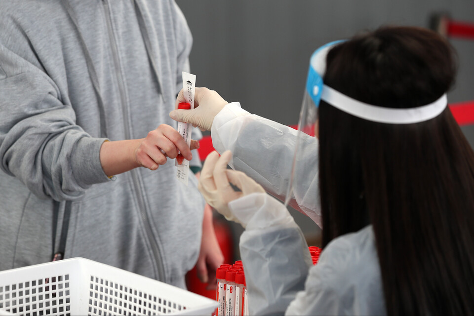 서울시 중구 서울역광장에 마련된 임시선별검사소에서 의료진이 시민에게 검체통을 건네고 있다. [사진제공=뉴시스]