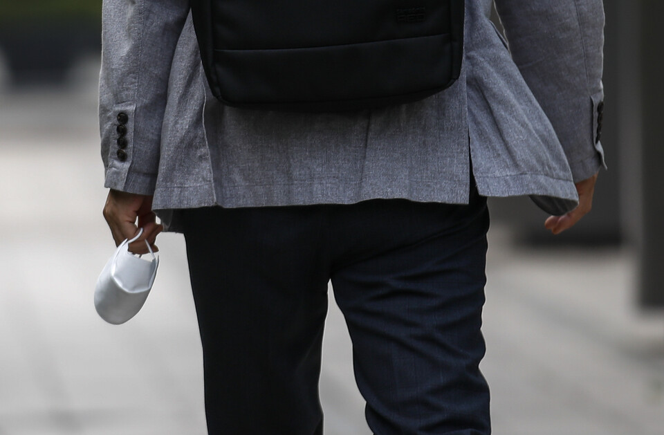 오전 서울 중구 청계광장 인근에서 한 시민이 마스크를 들고 이동하고 있다. [사진제공=뉴시스]