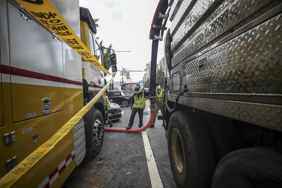 서울 서초구 서초대로 인근 빌딩에서 관계자들이 건물에서 물을 빼내고 있다. [사진제공=뉴시스]<br>