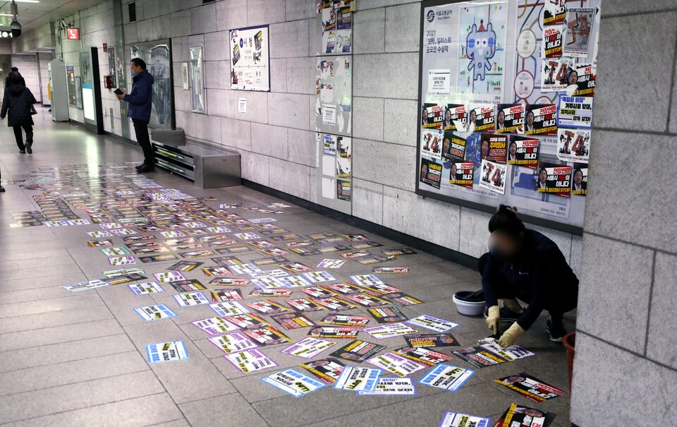27일 오후 서울의 한 지하철 역 승강장에서 지하철 환경미화원이 전장연 회원들이 붙여놓은 스티커를 제거하고 있다. [사진제공=뉴시스]