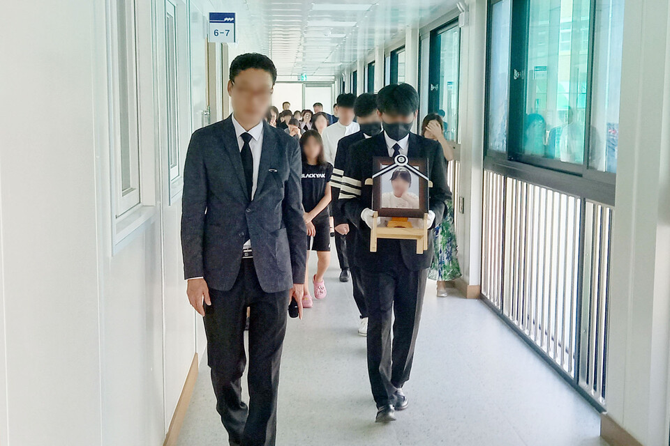 대전 여교사 운구차량이 지난 9일 근무하던 유성구 한 초등학교에 도착했다. 유족이 영정사진을 들고 생전에 담당했던 교실에서 내려오고 있다. [사진제공=뉴시스]