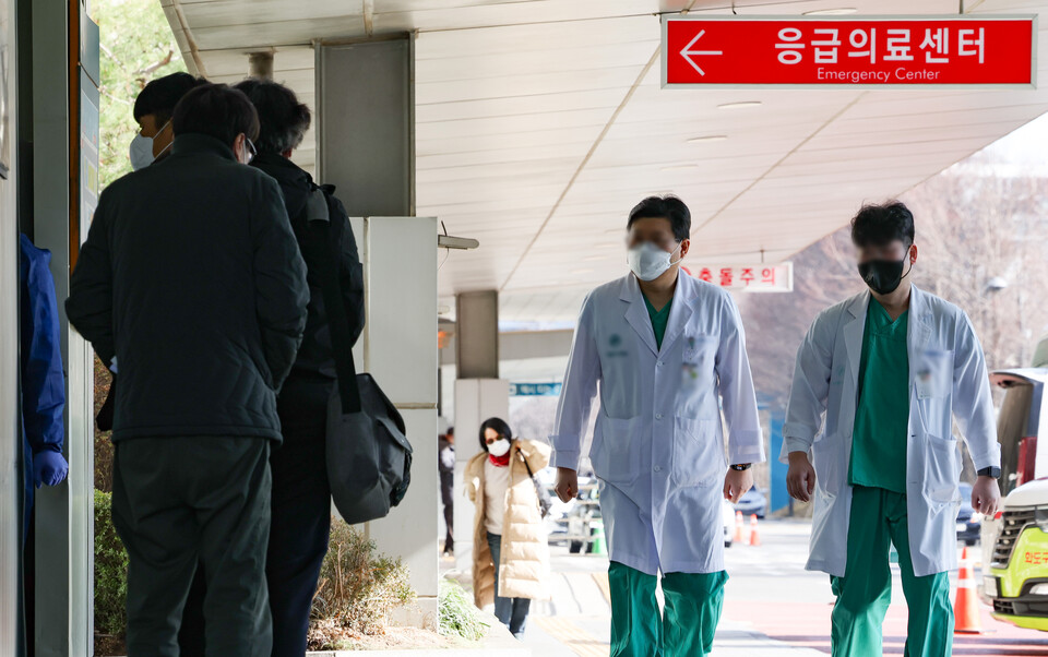 26일 서울 송파구 소재 모 병원 응급의료센터 앞에서 대기하는 환자들 옆으로 의료진이 걸어가고 있다. [사진제공=뉴시스]<br>