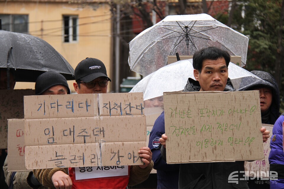 소나기가 쏟아지던 19일 오전 서울 동자동에서 열린 홈리스 주거권 보장을 위한 기자회견에서 홈리스 당사자들이 박스로 제작한 손팻말을 들고 있다.&nbsp;ⓒ투데이신문