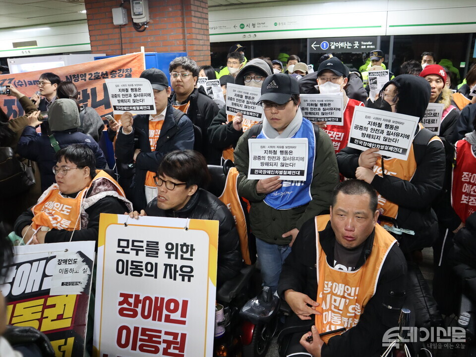 27일 오전 8시 서울 1호선 시청역 5-4 승강장에서 진행된 전국장애인차별철폐연대의 ‘제60차 출근길 지하철 탑니다’에서 참여자들이 피켓을 들고 있다. ⓒ투데이신문