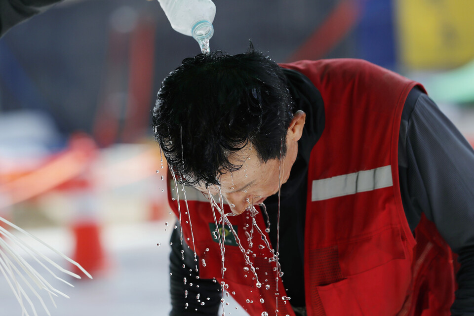 폭염이 이어졌던 지난해 8월 2일 인천국제공항 제2합동청사 확장 등 8동 시설공사 근로자가 물로 머리를 적시며 더위를 식히고 있다. [사진제공=뉴시스]