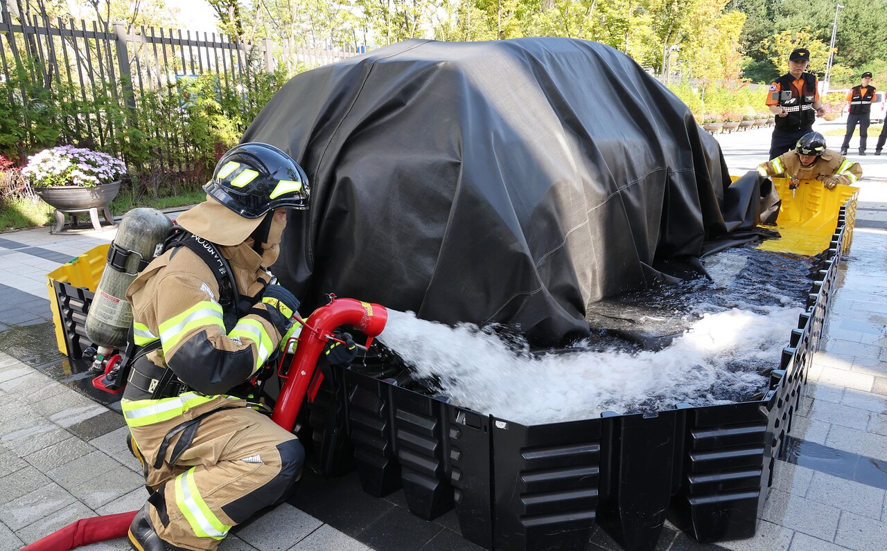 지난달 25일 세종시 정부세종청사에서 열린 2024년 중앙동 합동 소방훈련에서 소방관들이 전기차에 화재가 발생한 상황을 가정해 진압 시연을 하고 있다. [사진제공=행정안전부/뉴시스]