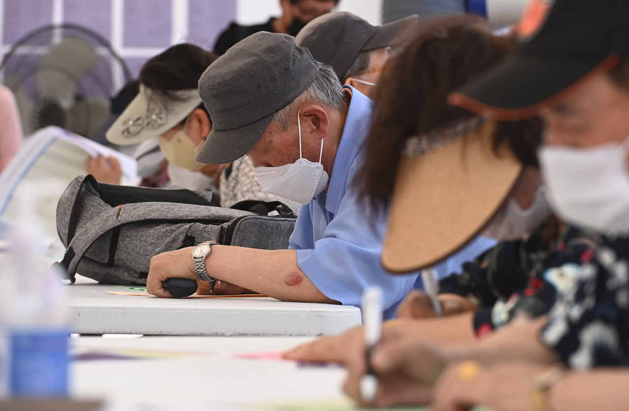 2022년 6월 21일 경기도 수원시 팔달구 화성행궁광장에서 진행된 ‘노인일자리 채용한마당’을 방문한 어르신들이 구직신청서를 쓰고 있다. [사진제공=뉴시스]<br>