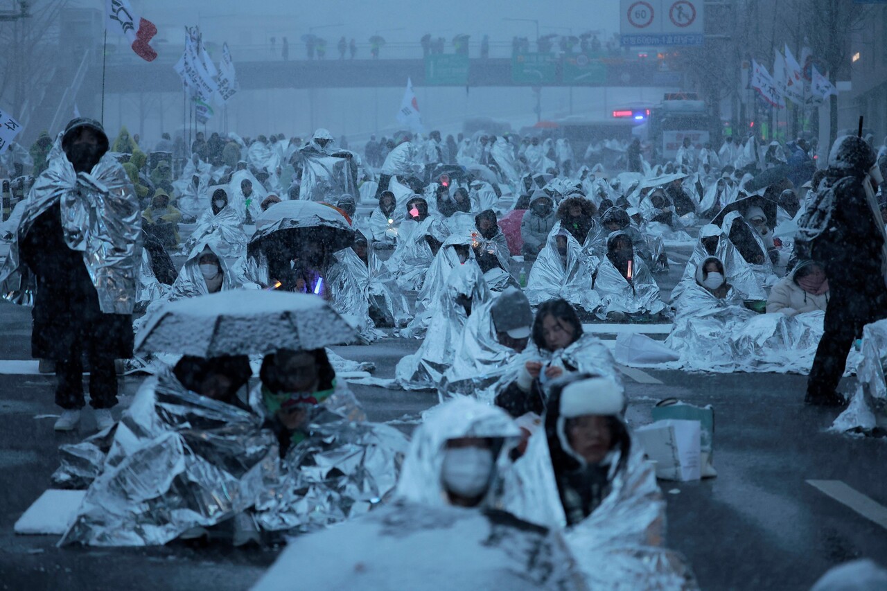 지난 5일 서울 용산구 대통령 관저 인근에서 열린 1박 2일 민주노총 철야투쟁에서 시민들이 은박 비닐을 덮은 채 도로에 착석해 있다. [사진제공=뉴시스]