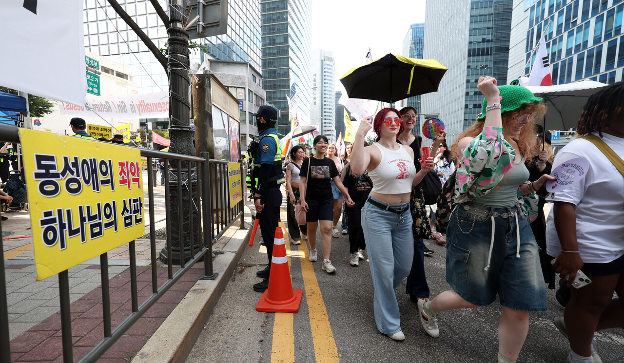 지난 14일 제26회 서울퀴어문화축제 참가자들이 퀴어퍼레이드를 하는 옆으로 기독교 단체 회원들이 반대 집회 현수막이 걸려 있다. [사진제공=뉴시스]