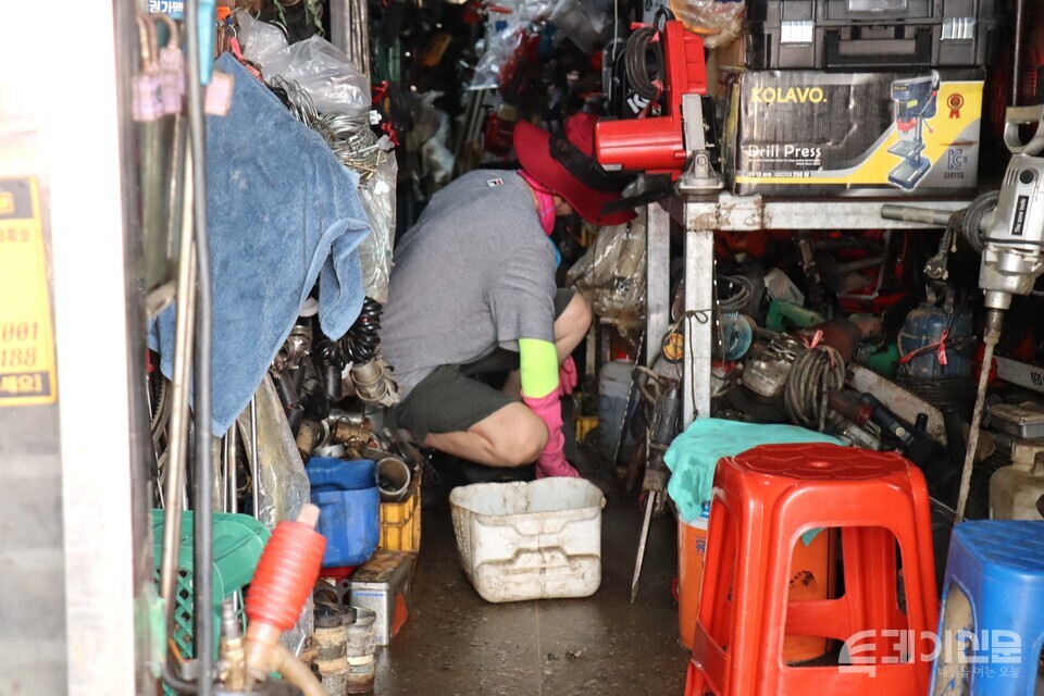 21일 오전 침수 피해를 입은 철물점 안에서 자원봉사자가 바닥을 닦고 있다. ⓒ투데이신문<br>